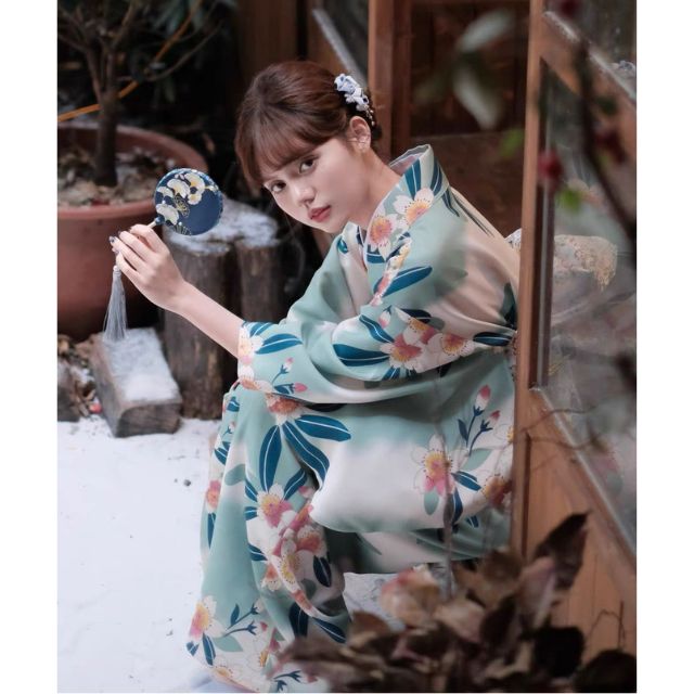 Floral kimono with teal and pink flower pattern worn in a traditional setting