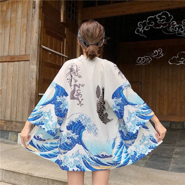 japanese wearing black kimono with wave and fish design against a light brick wall - eiyo kimono