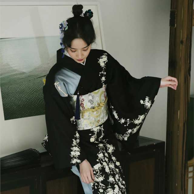 Black kimono with white floral pattern and wide sleeves in a traditional setting