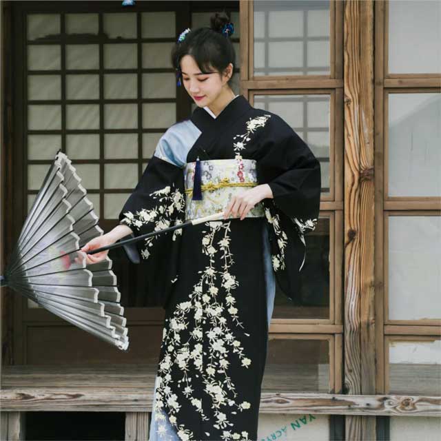 Black kimono with white floral pattern and wide sleeves in a traditional setting