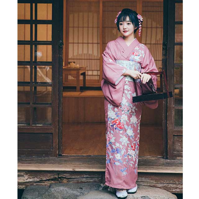 Woman in a pink floral kimono sitting in a traditional Japanese room.
