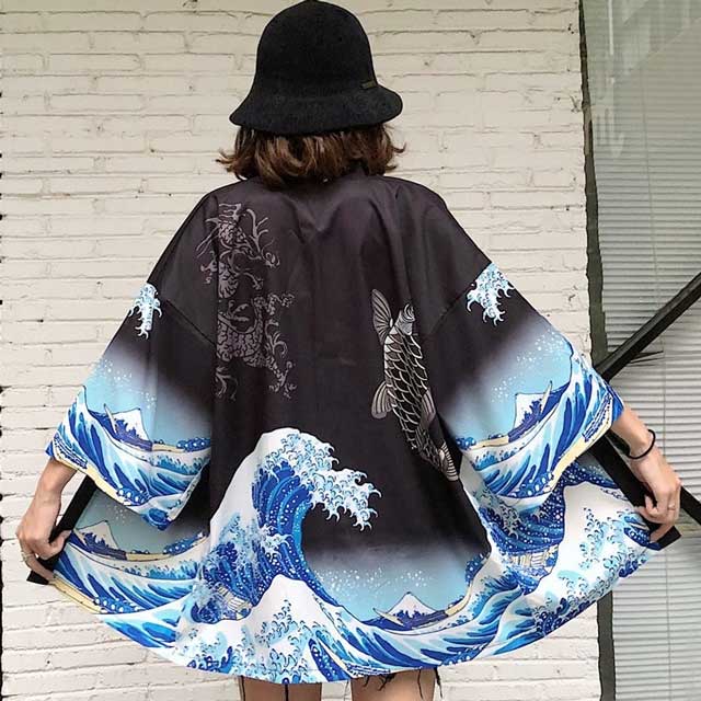 japanese wearing black kimono with wave and fish design against a light brick wall - eiyo kimono