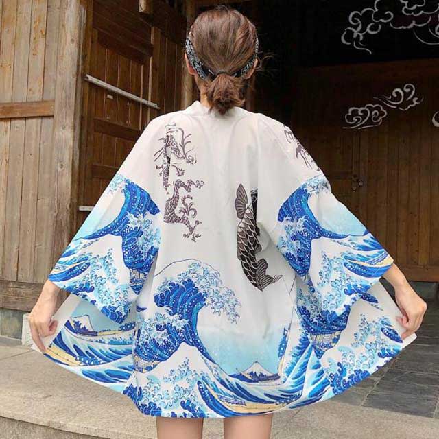 japanese wearing black kimono with wave and fish design against a light brick wall - eiyo kimono