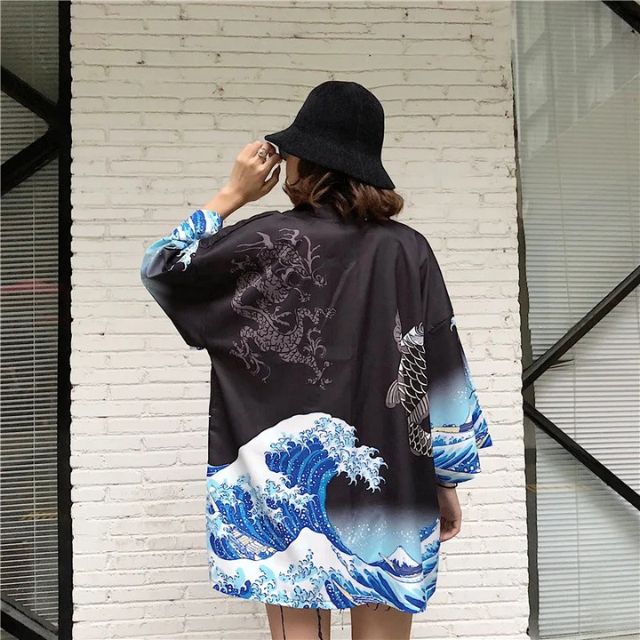 japanese wearing black kimono with wave and fish design against a light brick wall - eiyo kimono